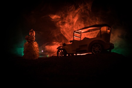 Silhouette of old vintage car and old style weared woman in dark foggy toned background with glowing...