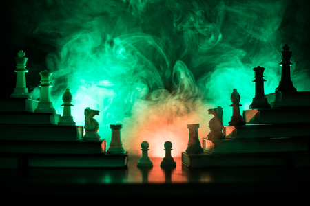 Business hierarchy. Strategy concept with chess pieces. Chess standing on a pyramid of books with the king at the top. Dark foggy background with toned light. Copy space.の写真素材
