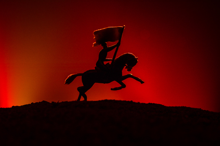 World war officer (or warrior) rider on horse with a sword ready to fight and soldiers on a dark foggy toned background. Battle scene battlefield of fighting soldiers. Selective focusの写真素材