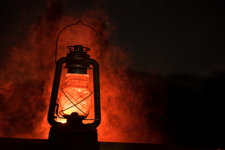 Horror Halloween concept. Burning old oil lamp in forest at night. Night scenery of a nightmare scene. Selective focus.の写真素材