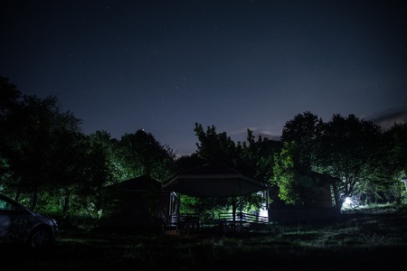 Mountain night landscape of building at forest at night with moon or vintage country house at night...