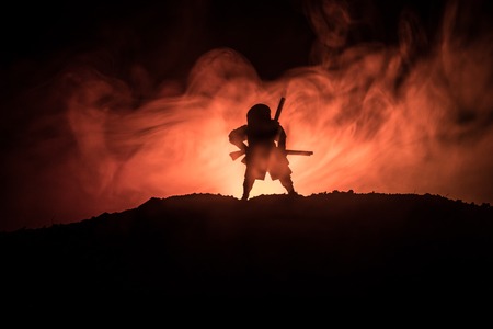 Fighter with a sword silhouette a sky ninja. Samurai on top of mountain with dark toned foggy background. Selective focusの写真素材