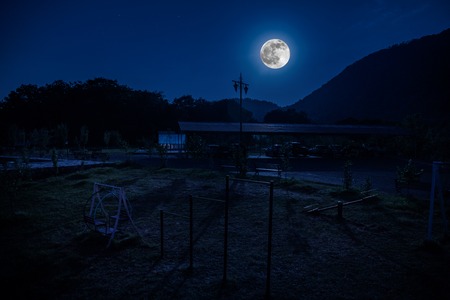 Mountain night landscape of building at forest at night with moon or vintage country house at night...