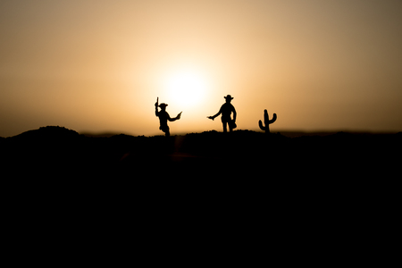 Cowboy concept. Silhouette of Cowboys at sunset time. Cowboys silhouettes on a hill with horses. Selective focusの写真素材