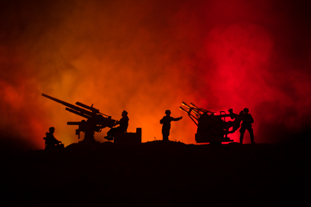 An anti-aircraft cannon and Military silhouettes fighting scene on war fog sky background, World War Soldiers Silhouettes Below Cloudy Skyline at nightの写真素材
