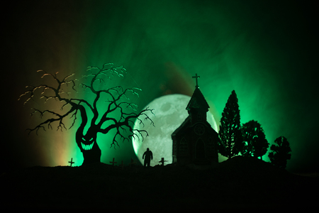 Scary view of zombies at cemetery dead tree, moon, church and spooky cloudy sky with fog, Horror Halloween concept. Tonedの写真素材