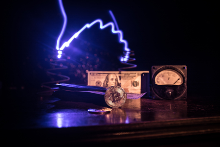 Energy for mining cryptocurrency. The energy meter with bitcoin and money on dark toned foggy background. Power Counter Meter Voltage Measuring Outlet Power consumption of Mining Rig. Selective focusの写真素材