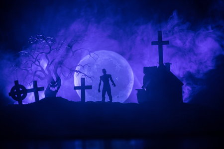 Scary view of zombies at cemetery dead tree, moon, church and spooky cloudy sky with fog, Horror Halloween concept. Tonedの写真素材