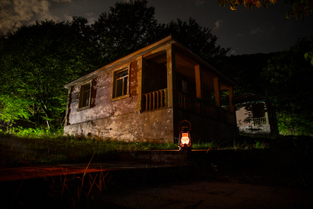 Mountain night landscape of building at forest at night with moon or vintage country house at night with clouds and stars. Summer night. Photo taken with long exposureの写真素材
