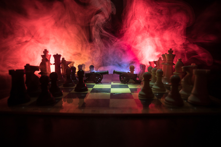 Medieval battle scene with two cannon on chessboard. Chess board game concept of business ideas and competition and strategy ideas Chess figures on a dark background with smoke and fog.の写真素材
