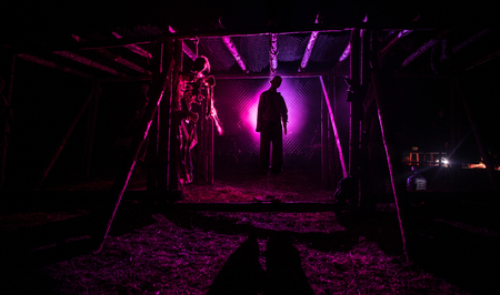 Horror view silhouette of hanged man on scaffold at night with fog and toned light on background.