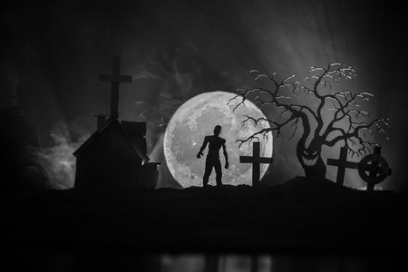 Scary view of zombies at cemetery dead tree, moon, church and spooky cloudy sky with fogの写真素材