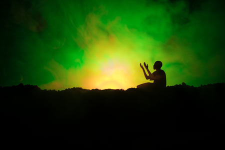 Silhouette of praying Muslim man on toned foggy background.の写真素材