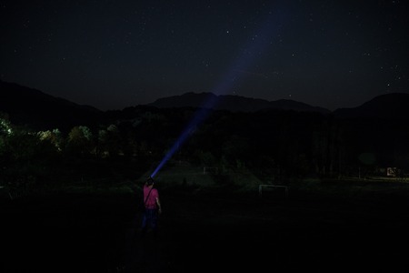 Silhouette of man in the forest on the night. Silhouette of person standing in the dark forest with light. Dark night in forest. Surreal night forest scene. Horror Halloween concept.の写真素材