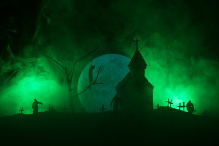 Scary view of zombies at cemetery dead tree, moon, church and spooky cloudy sky with fog, Horror Halloween concept.の写真素材