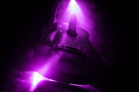 Music concept. Acoustic guitar on a dark background under beam of light with smoke with copy space....