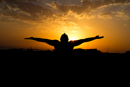 Silhouette of man with their hands in the sunset.の写真素材