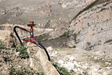 Hookah, traditional arabic waterpipe, direct sunset light, outdoor photo. Mountain background....