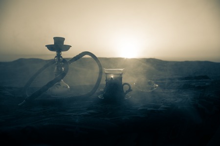 Hookah hot coals on shisha bowl making clouds of steam at desert outdoor. Oriental ornament on the...
