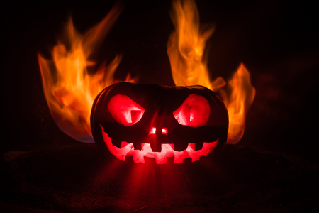 Halloween pumpkin smile and scrary eyes for party night. Close up view of scary Halloween pumpkin with eyes glowing inside at black background. Selective focusの写真素材