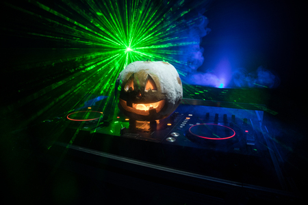 Halloween pumpkin on a dj table with headphones on dark background with copy space. Happy Halloween festival decorations and music concept. Empty space. Selective focusの写真素材