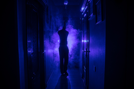 Creepy silhouette in the dark abandoned building. Horror Halloween concept. Dark corridor with silhouette of horror person standing in center. Toned light and fog on background.の写真素材