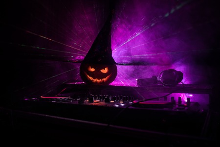 Halloween pumpkin on a dj table with headphones on dark background with copy space. Happy Halloween festival decorations and music concept. Empty space. Selective focusの写真素材