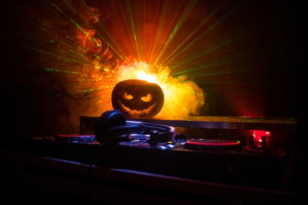 Halloween pumpkin on a dj table with headphones on dark background with copy space. Happy Halloween festival decorations and music concept. Empty space. Selective focusの写真素材