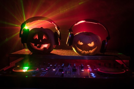 Halloween pumpkin on a dj table with headphones on dark background with copy space. Happy Halloween festival decorations and music concept. Empty space. Selective focusの写真素材