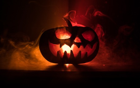 Halloween pumpkin smile and scrary eyes for party night. Close up view of scary Halloween pumpkin with eyes glowing inside at black background. Selective focusの写真素材
