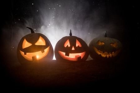 Group of Halloween Jack o Lanterns at night with a rustic dark foggy toned background. Selective focusの写真素材