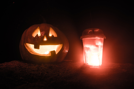 Halloween pumpkin orange cocktails. Festive drink. Halloween party. Funny Pumpkin with a glowing cocktail glass on a dark toned foggy background. Selective focusの写真素材