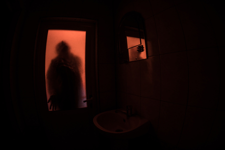 Horror silhouette of woman in window. Scary halloween concept Blurred silhouette of witch in bathroomの写真素材