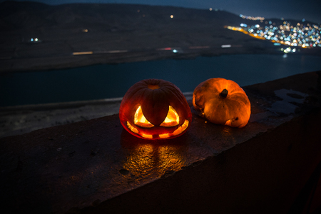 Horror Halloween concept. Close up view of scary dead Halloween pumpkin glowing at dark background. Rotten pumpkin head. Selective focusの写真素材