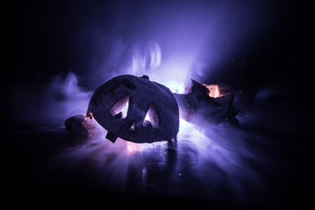 Horror Halloween concept. Close up view of scary dead Halloween pumpkin glowing at dark background. Destroyed pumpkin. Selective focusの写真素材