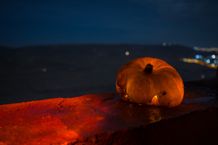 Horror Halloween concept. Close up view of scary dead Halloween pumpkin glowing at dark background. Rotten pumpkin head. Selective focusの写真素材