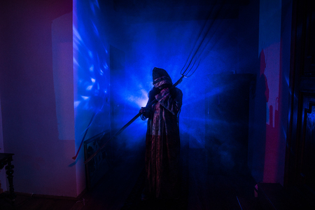 Horror silhouette of ghost inside dark room with mirror. Scary halloween concept. Silhouette of witch inside haunted house with fog and light on background. Selective focusの写真素材