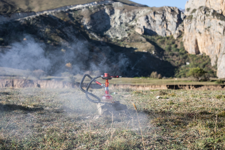 Hookah, traditional arabic waterpipe, direct sunset light, outdoor photo. Mountain background. Outdoor. Empty space.の写真素材