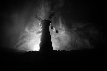 Windmill silhouette standing on hill against the night sky. Night decor with old windmill on hill with horror toned foggy background with light. Horror conceptの写真素材