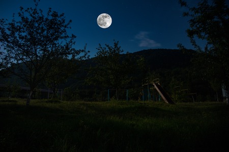 Mountain Road through the forest on a full moon night. Scenic night landscape of dark blue sky with moonの写真素材