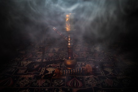 Hookah hot coals on shisha bowl making clouds of steam at Arabian interior. Oriental ornament on the carpet. Stylish oriental shisha with backlight. For Shisha advertisement. Selective focusの写真素材