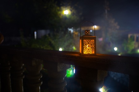 Retro style lantern at night. Beautiful colorful illuminated lamp at the balcony in the garden. Selective focusの写真素材