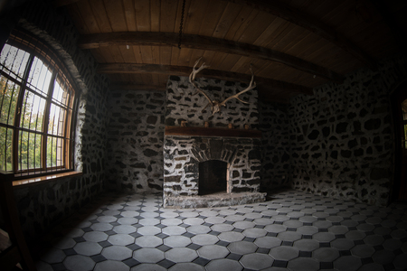 Backdrop of a brick fireplace wall in a vacant setting. Dark room with big windows and fireplaceの写真素材