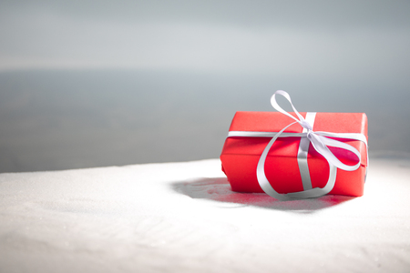 Christmas or New Year gift with ribbon in snow on bokeh background. Copy space for text. Winter card. Holiday and celebration concept.の写真素材