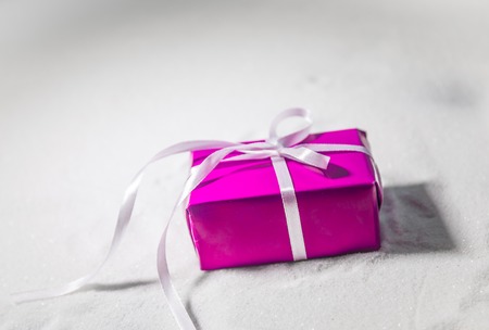 Christmas or New Year gift with ribbon in snow on bokeh background. Copy space for text. Winter card. Holiday and celebration concept.の写真素材