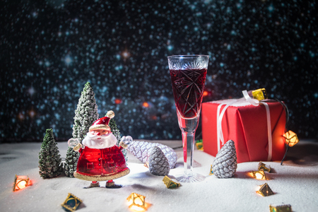 Glass of wine with Christmas decoration. Red wine in crystal glass on snow with creative New Year artwork. Copy spaceの写真素材