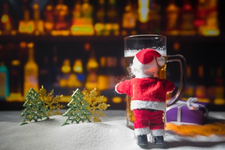 Mug of beer with Christmas decoration. Glass of light beer with foam in snow with creative New Year...