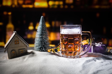 Mug of beer with Christmas decoration. Glass of light beer with foam in snow with creative New Year holiday artwork. Copy spaceの写真素材