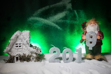 Christmas and New Year miniature house in the snow at night with fir tree. Little toy house on snow with tree. Festive background. Christmas decorations. Holiday concept.の写真素材