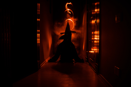 Creepy silhouette in the dark abandoned building. Horror Halloween concept. Dark corridor with silhouette of horror person standing in center. Toned light and fog on background.の写真素材